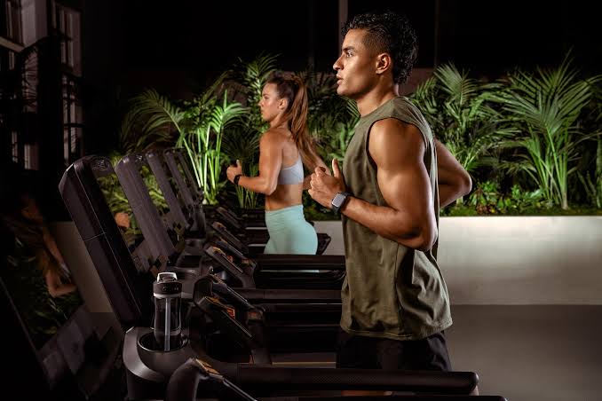Two people running on treadmills in a gym